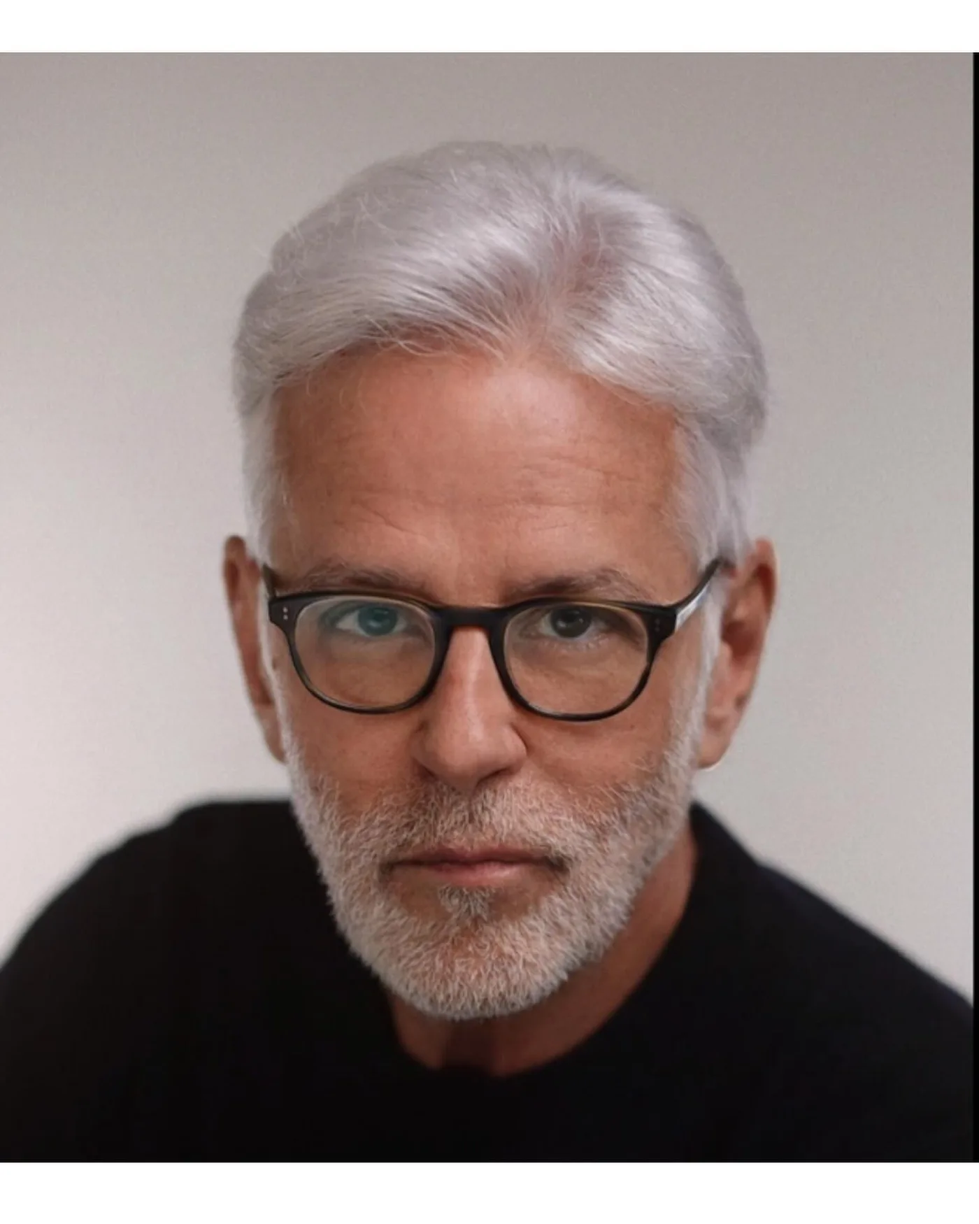 John Amedro, New York character actor, silver-haired, bearded, in glasses and a black crewneck, looking directly at camera