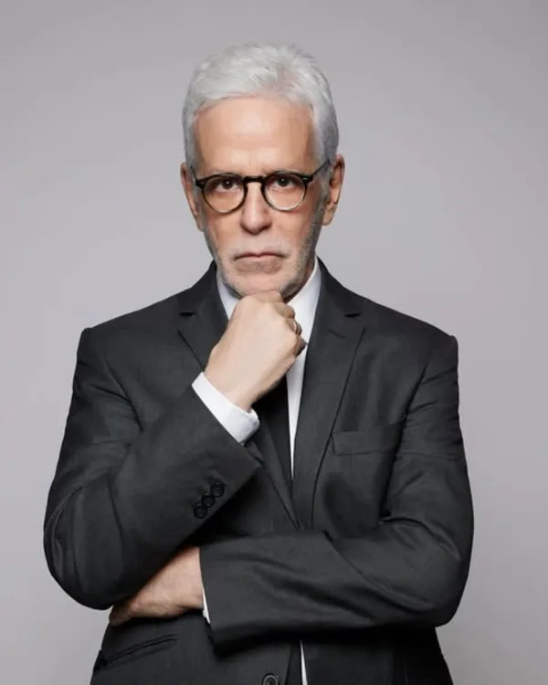 John Amedro theatrical headshot, arms crossed in a dark suit